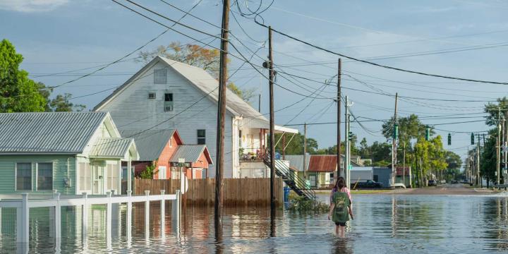 two people walking in a flooded street with houses
